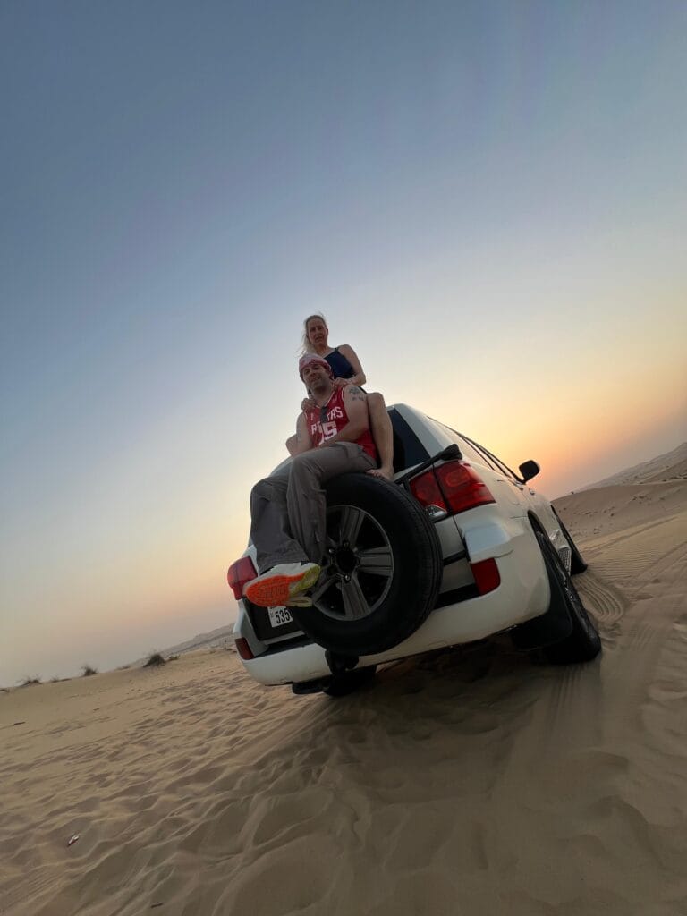 Tourists enjoying evening desert safari in Abu Dhabi with dune bashing and sunset views