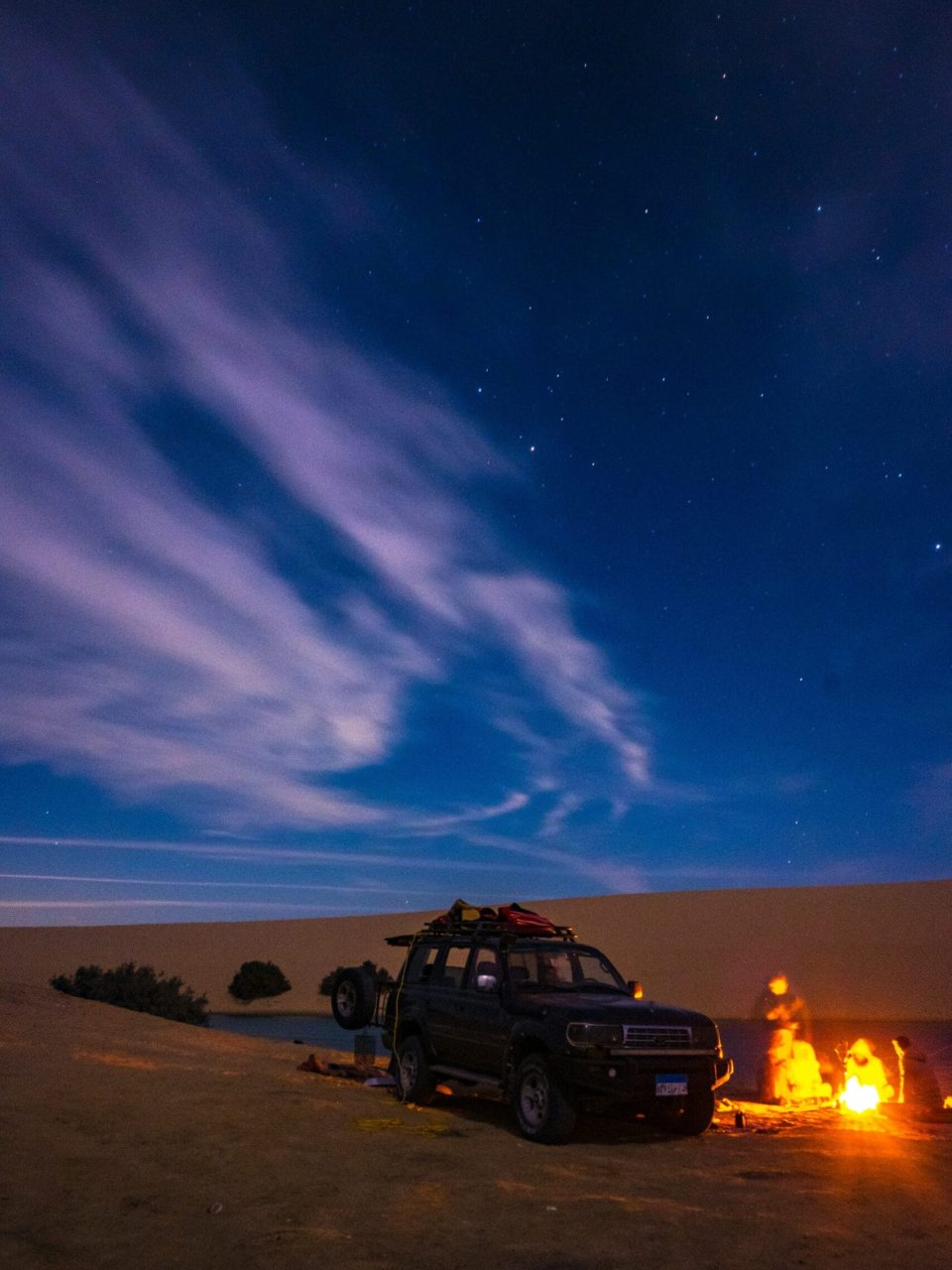 Guests enjoying overnight desert safari in Abu Dhabi with campfire and desert tents
